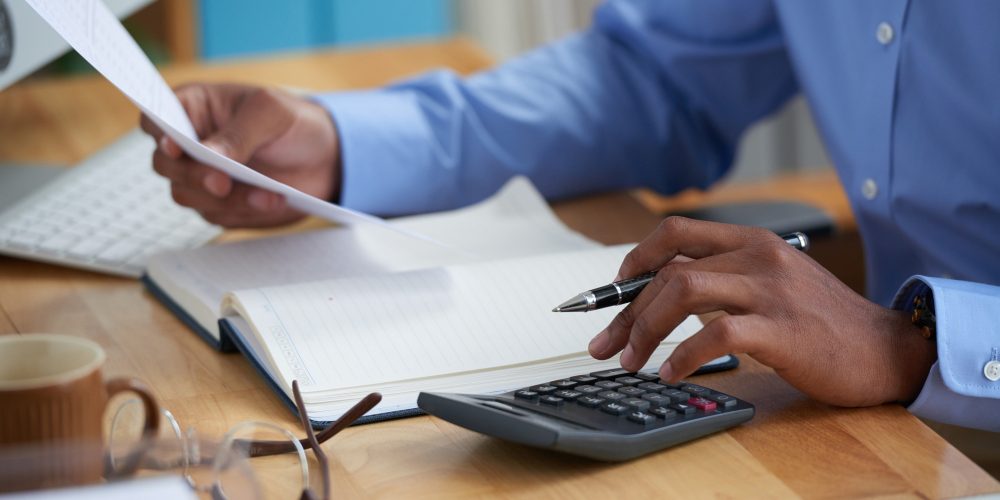 Gentleman of African descent looking at a document while on his calculator | KRA Pin registration services in Kenya | Business registration services in Nairobi