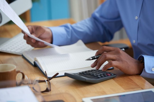 The indispensable KRA Pin, the key to business success in Kenya for Kenyans, & foreign resident Entrepreneurs Gentleman of African descent looking at a document while on his calculator | KRA Pin registration services in Kenya | Business registration services in Nairobi